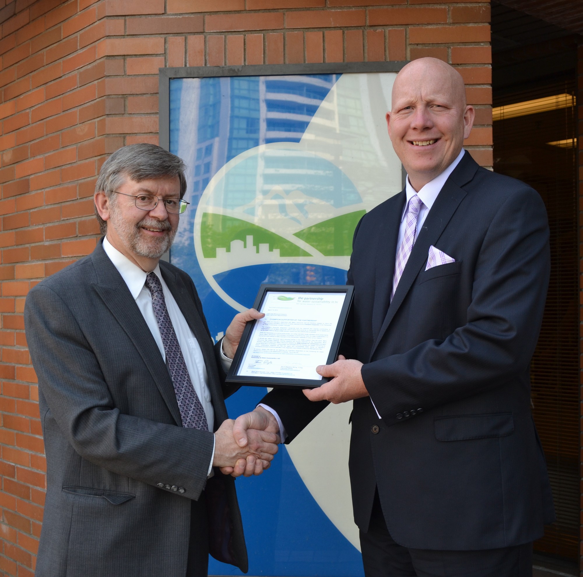 Kim Stephens (L), Executive Director of the Partnership for Water Sustainability, presents the “letter of recognition” to Metro Vancouver Chair Greg Moore (R) in May 2014